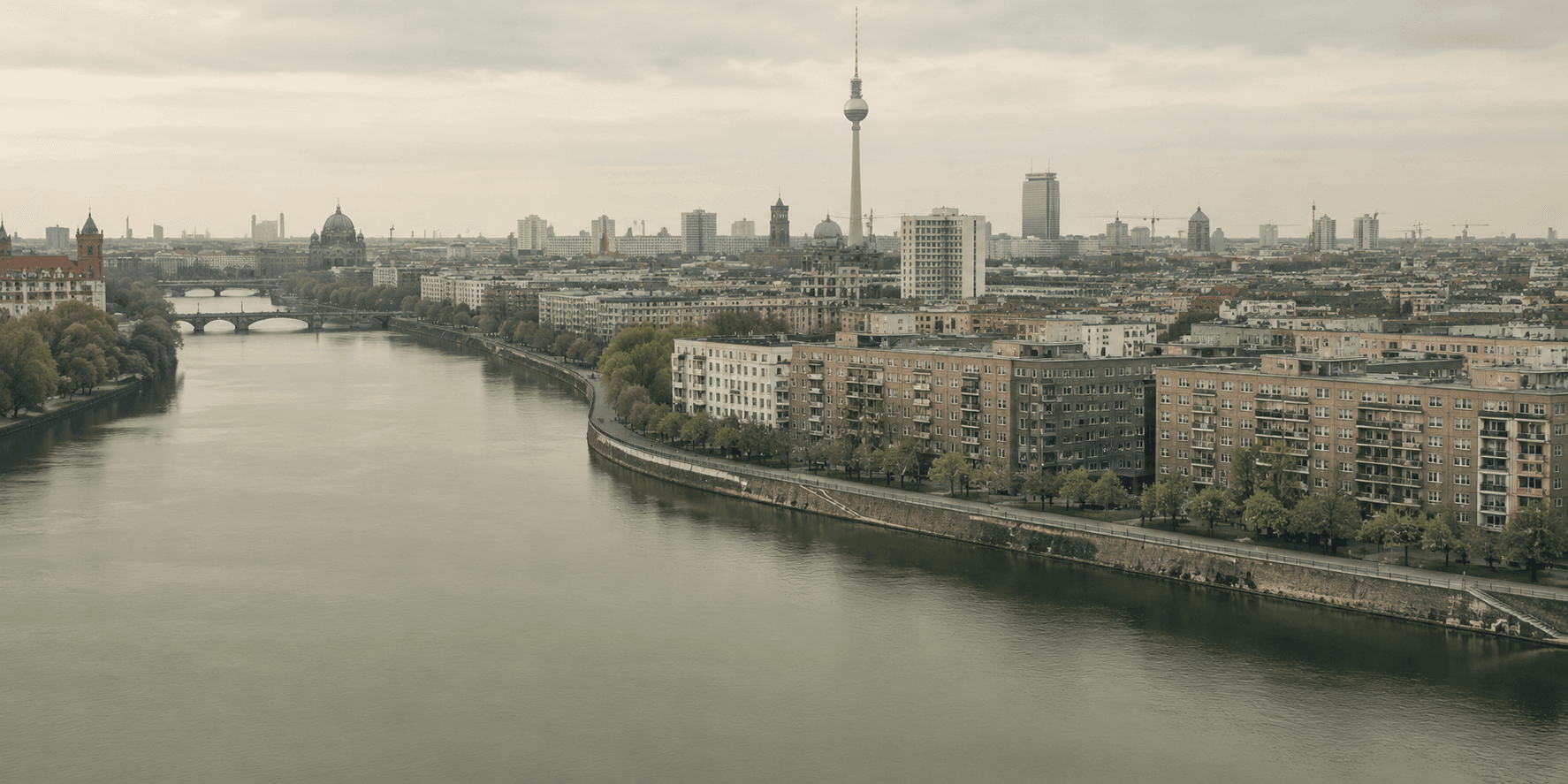 Übersichtsbild von Berlin mit Spreeufer und Spree, sowie Häuserblöcke dahinter und am Horizont markant der Fernsehturm.